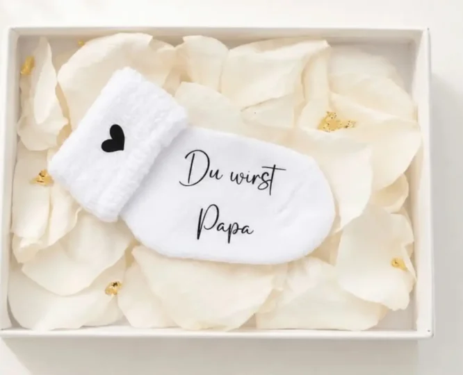 Personalisierte Schwangerschaftsverkündungssocke in eleganter Geschenkbox mit Rosenblättern und Blattgold – liebevolles und einzigartiges Babyankündigungs-Geschenk