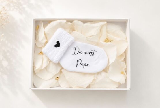 Personalisierte Schwangerschaftsverkündungssocke in eleganter Geschenkbox mit Rosenblättern und Blattgold – liebevolles und einzigartiges Babyankündigungs-Geschenk