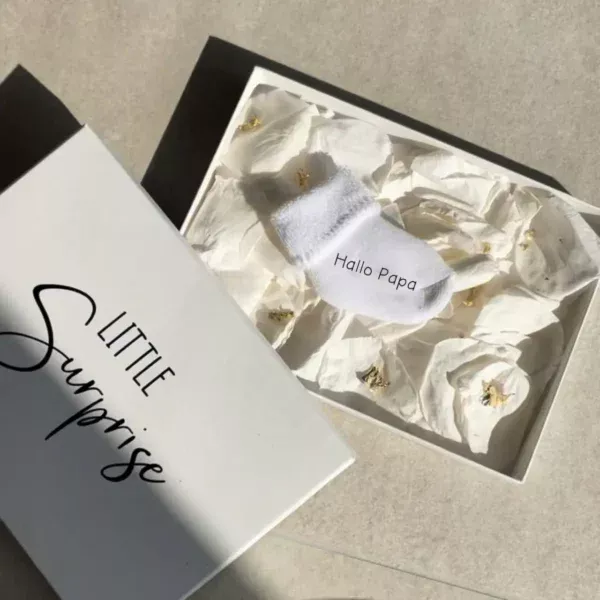 Personalisierte Schwangerschaftsverkündungssocke in eleganter Geschenkbox mit Rosenblättern und Blattgold – liebevolles und einzigartiges Babyankündigungs-Geschenk