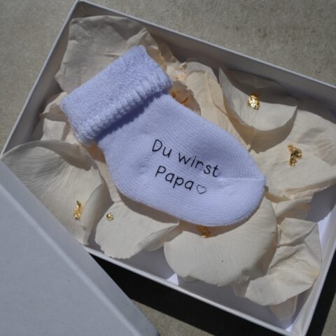 Personalisierte Schwangerschaftsverkündungssocke in eleganter Geschenkbox mit Rosenblättern und Blattgold – liebevolles und einzigartiges Babyankündigungs-Geschenk
