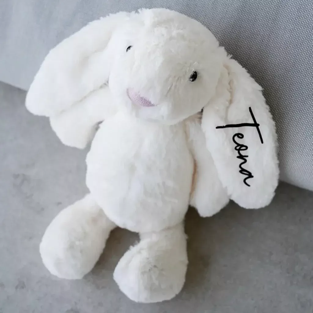 Weisser Plüschhase mit bedrucktem Namen auf dem Ohr, kuscheliges Stofftier als personalisiertes Geschenk zur Geburt oder Taufe
