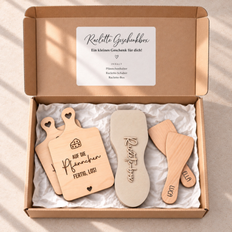 Offene braune Geschenkbox mit Raclette-Spachteln für Luca und Ella, zwei Holz-Pfännchenhaltern und einer beigen Raclette-Box